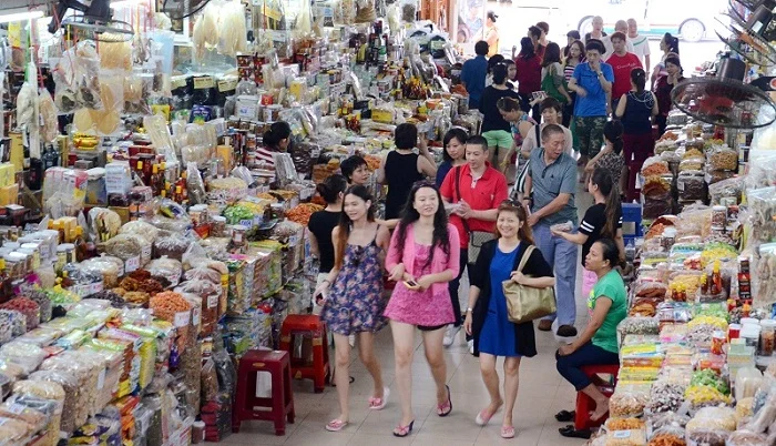 Shoppers walking an aisle lined with dried goods and snacks at Đông Kinh market