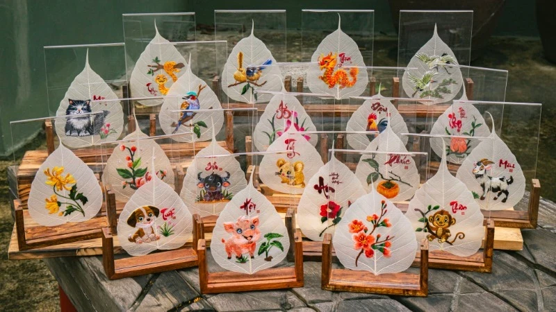 Hand-embroidered pictures on leaves, displayed in small wooden stands